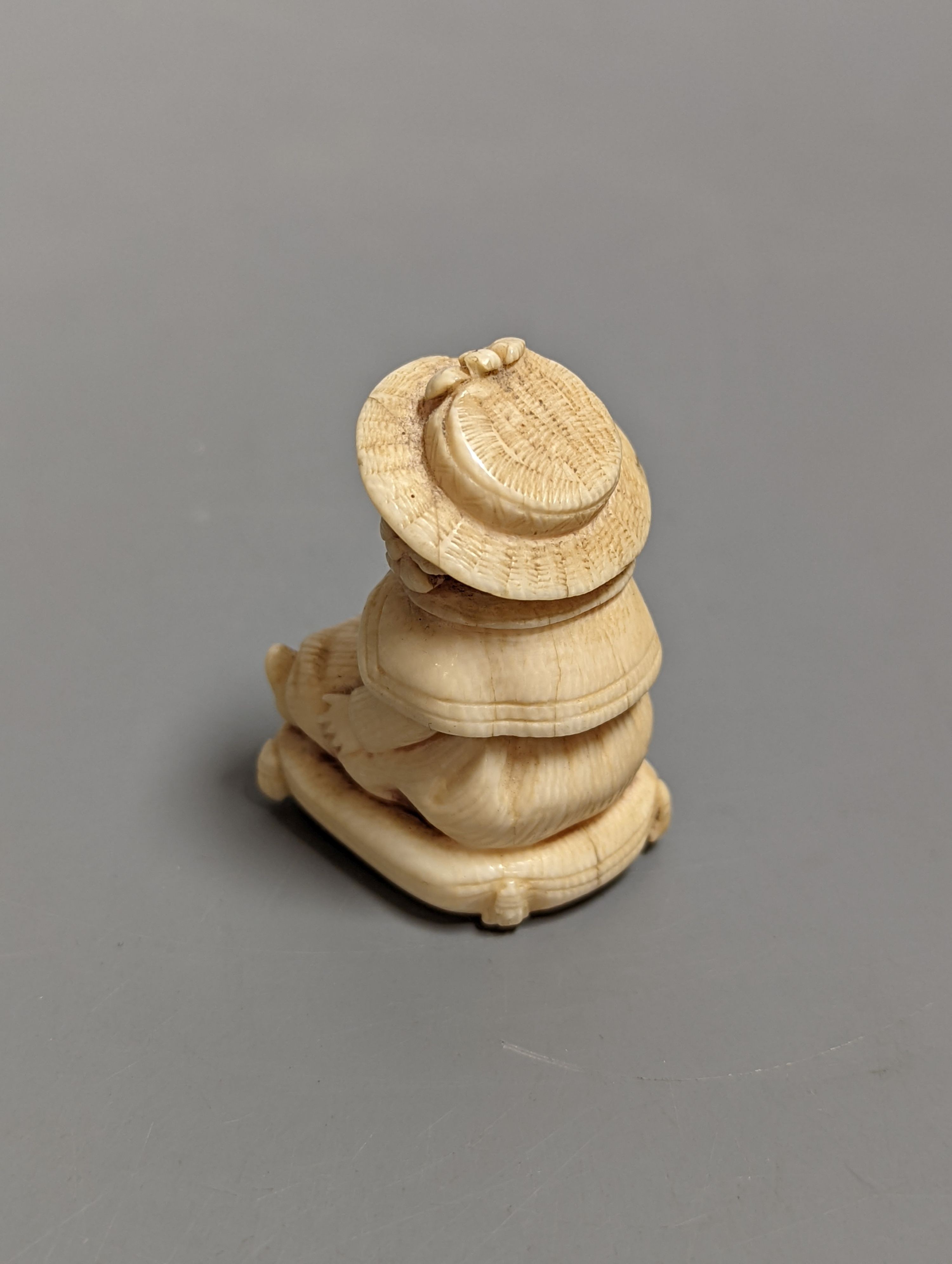 A late 19th/early 20th century carving of a girl seated on a cushion, 5 cms high